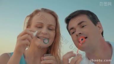 斯坦尼康慢动作拍摄的年轻夫妇吹肥皂泡，他们站在海滩上彼此靠近
